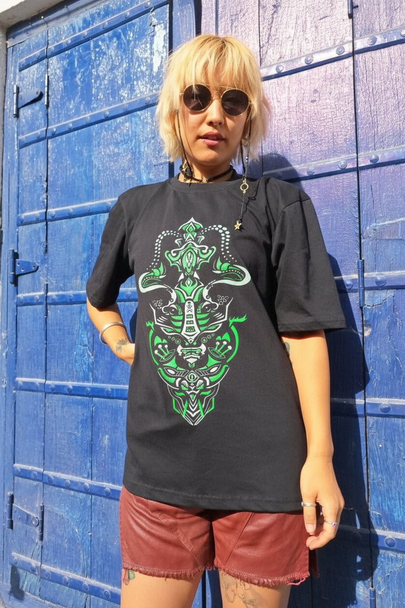 Person wearing a black t-shirt with green graphic design in front of a blue wall.