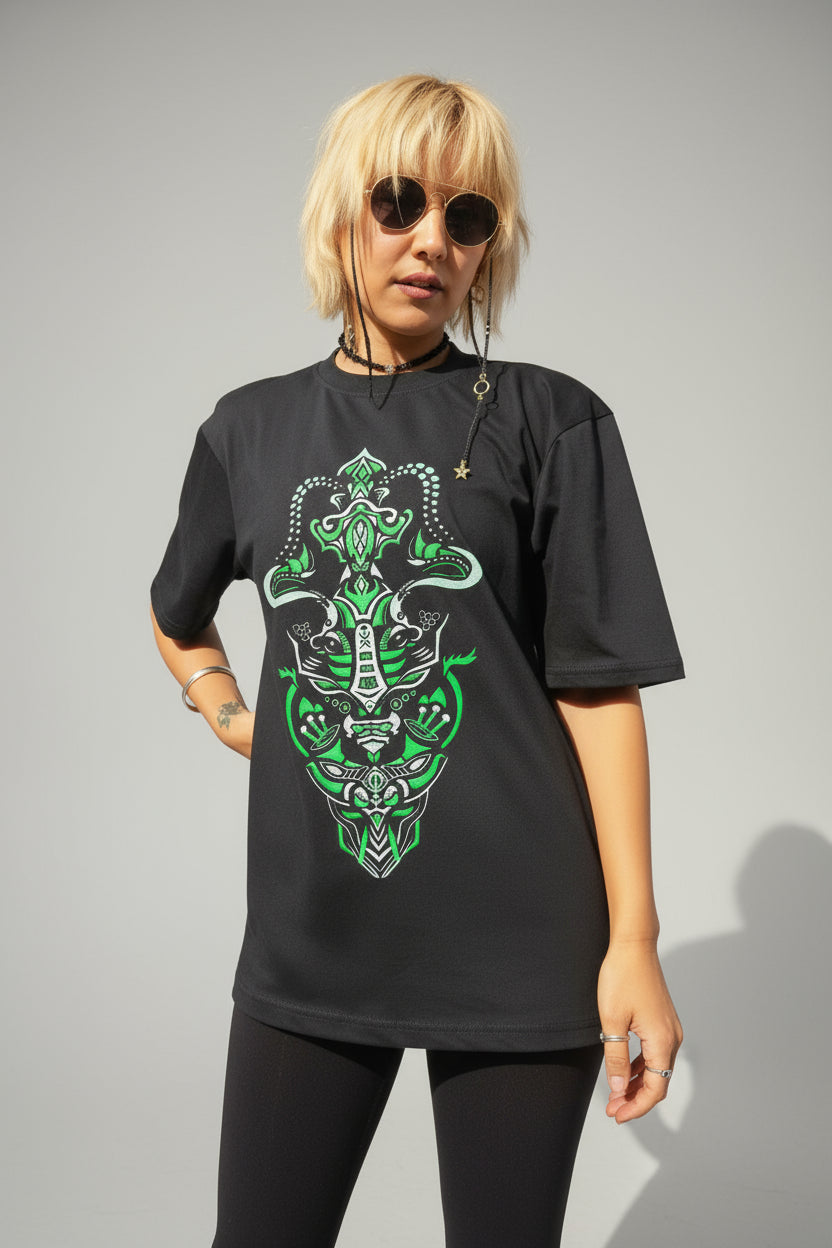 Person wearing a black t-shirt with green graphic design in front of a blue wall.