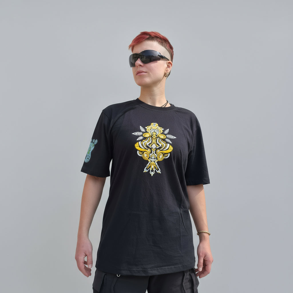 Person wearing a black t-shirt with a yellow and white design against a textured wall.